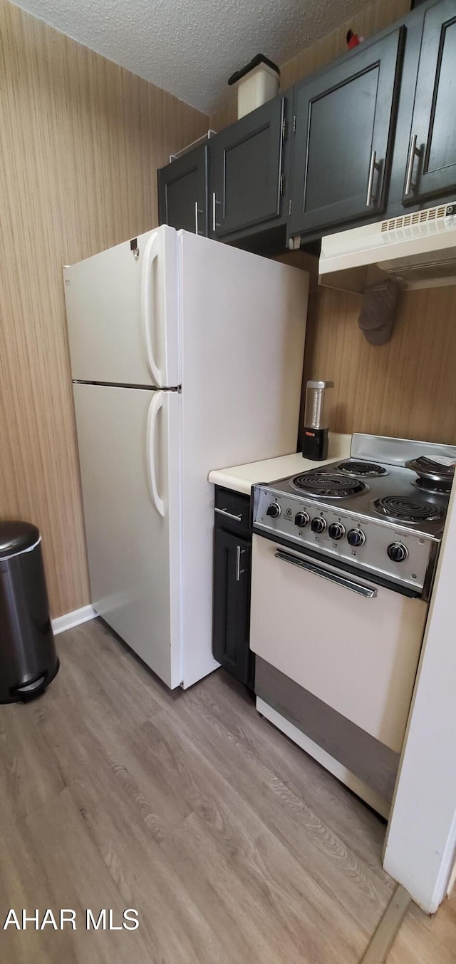 kitchen with electric range, white fridge, wooden walls, a textured ceiling, and light hardwood / wood-style flooring