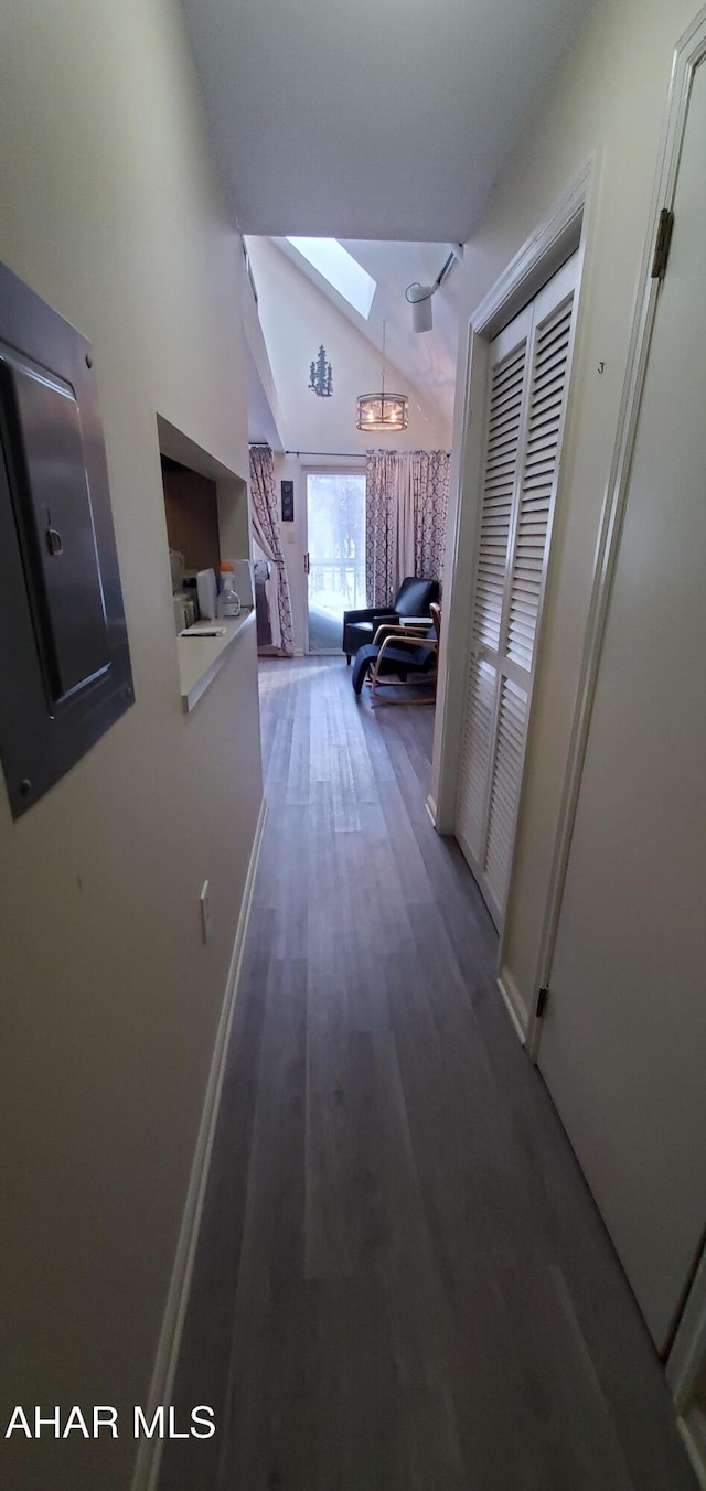 corridor with dark hardwood / wood-style flooring and vaulted ceiling with skylight