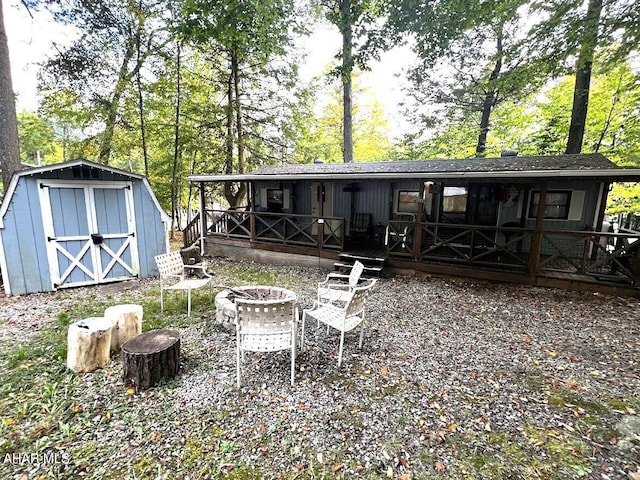 back of house featuring a fire pit, a shed, and a wooden deck