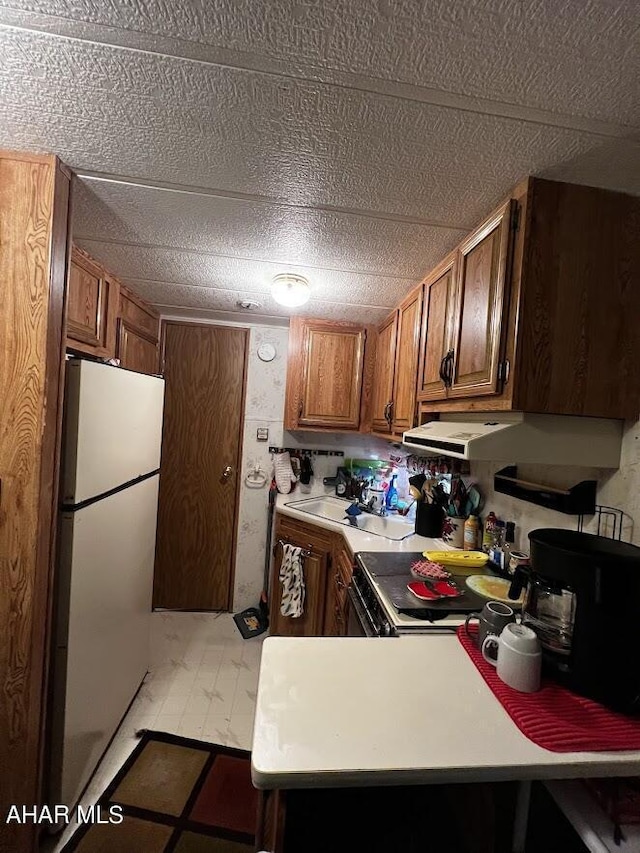 kitchen with kitchen peninsula, electric range, white fridge, and range hood