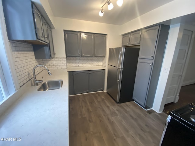 kitchen with freestanding refrigerator, a sink, gray cabinets, light countertops, and tasteful backsplash
