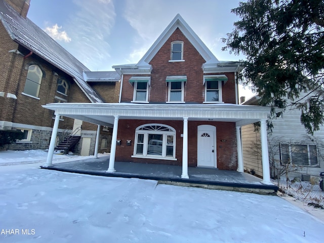view of property with covered porch and brick siding