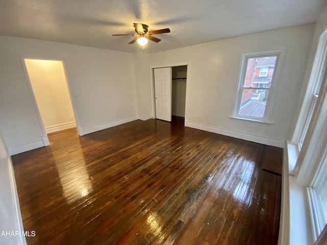 unfurnished bedroom with dark wood finished floors, baseboards, a closet, and a ceiling fan