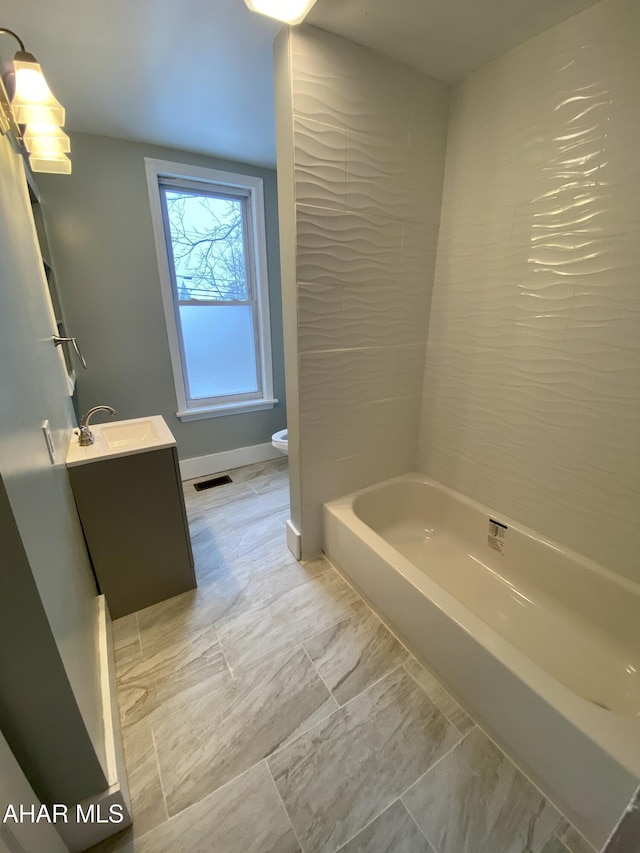 full bath featuring toilet, vanity, and baseboards