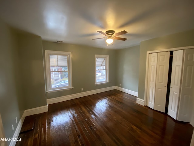 unfurnished bedroom with dark wood finished floors, baseboards, a closet, and ceiling fan