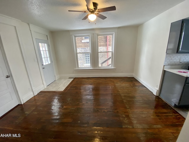 unfurnished dining area featuring hardwood / wood-style flooring, ceiling fan, a textured ceiling, and baseboards