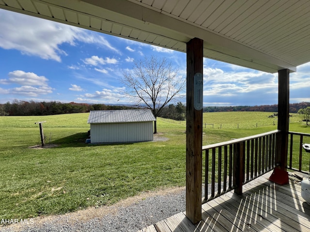 deck featuring a lawn, a storage unit, and a rural view