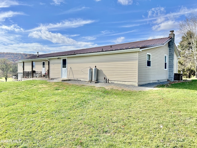 back of property with central AC unit, a patio area, and a yard