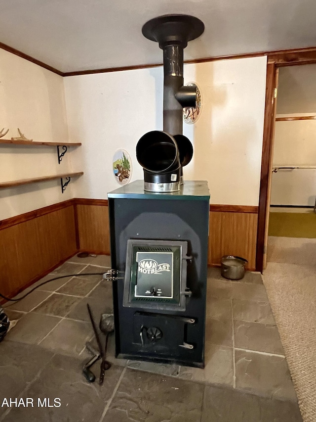 interior details with carpet floors, a wood stove, ornamental molding, and wood walls