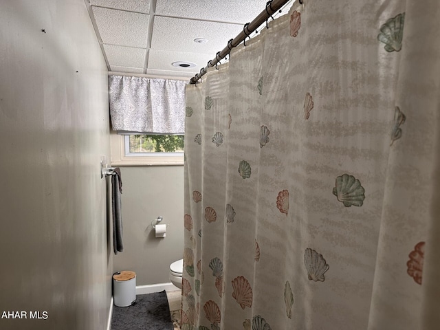 bathroom with a paneled ceiling, curtained shower, and toilet