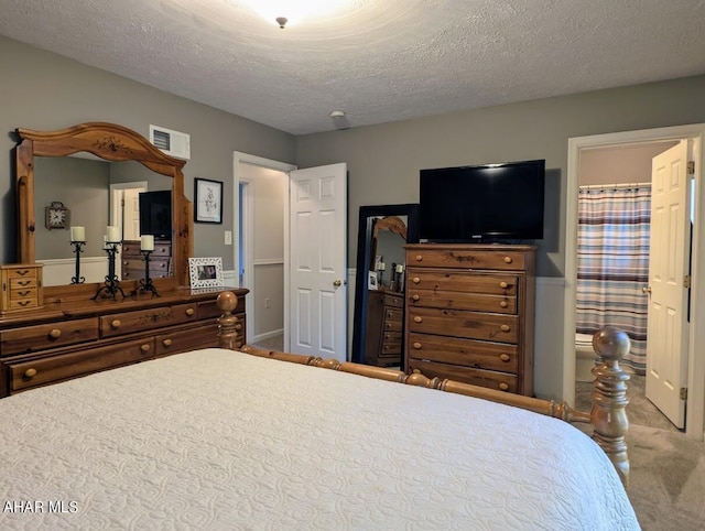 bedroom featuring carpet, a textured ceiling, and connected bathroom