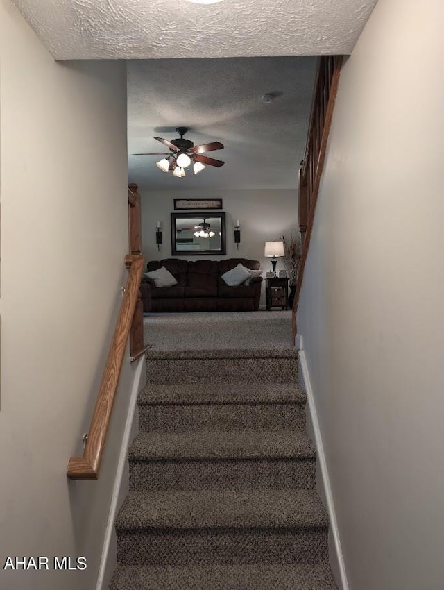 staircase featuring carpet, a textured ceiling, and ceiling fan