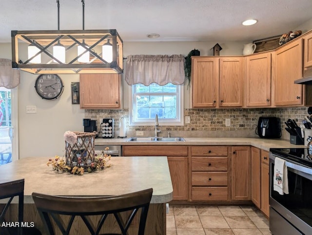 kitchen with backsplash, sink, stainless steel range with electric cooktop, and decorative light fixtures