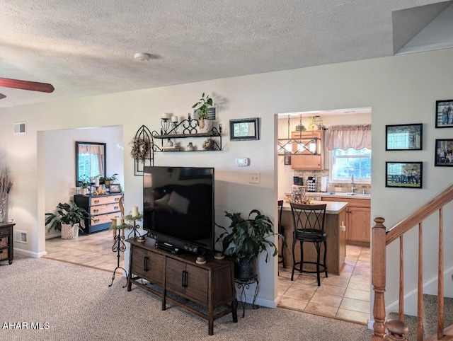 carpeted living room with ceiling fan, sink, and a textured ceiling