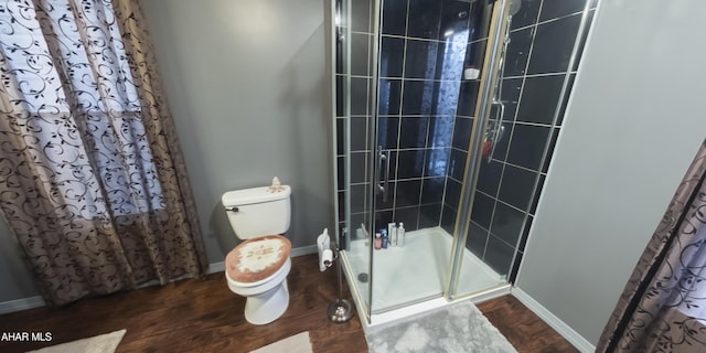 bathroom featuring hardwood / wood-style floors, toilet, and a shower with shower door