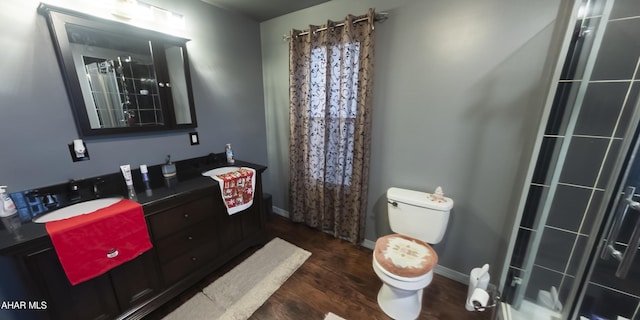 bathroom with walk in shower, hardwood / wood-style floors, vanity, and toilet