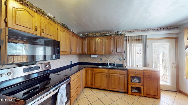 kitchen with brown cabinetry, stainless steel electric stove, a healthy amount of sunlight, and black microwave