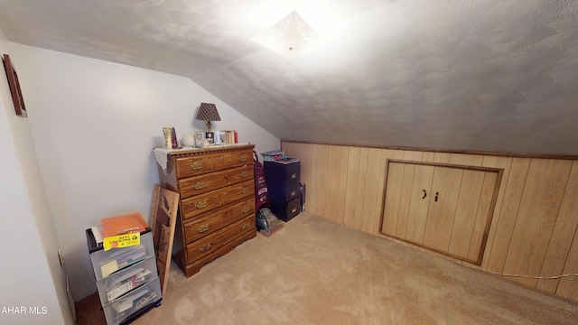 bonus room with wooden walls, light colored carpet, a textured ceiling, and lofted ceiling