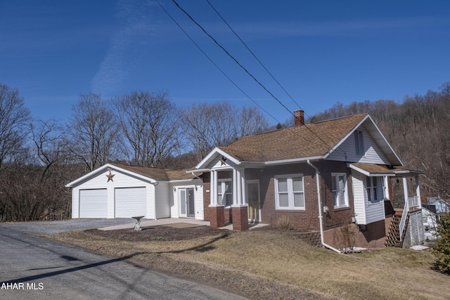 bungalow-style house with a shingled roof, a front yard, an attached garage, brick siding, and a chimney