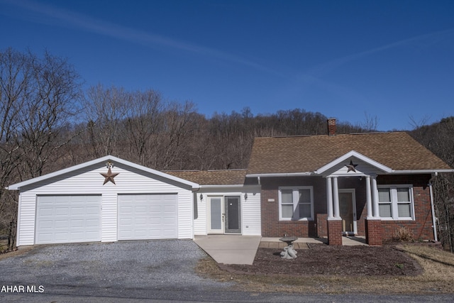 view of front facade featuring a garage, brick siding, roof with shingles, and a chimney