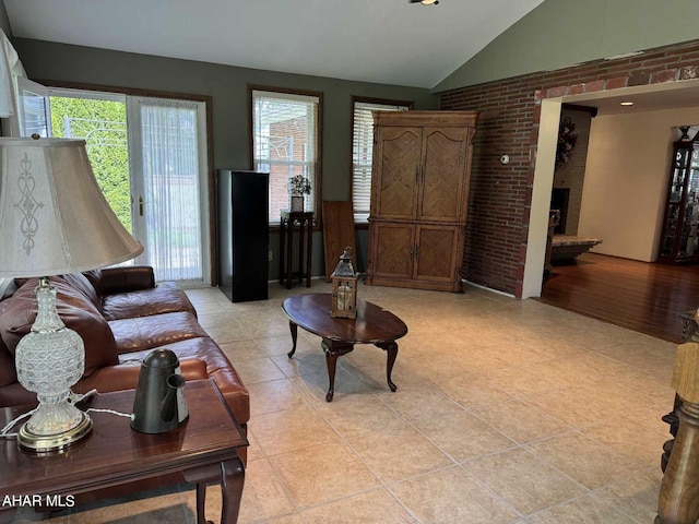 living room with a brick fireplace, light hardwood / wood-style flooring, lofted ceiling, and brick wall