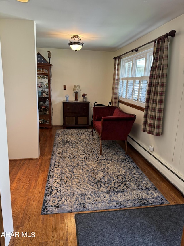 sitting room featuring wood-type flooring and a baseboard heating unit