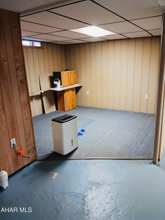 basement with wooden walls and a drop ceiling