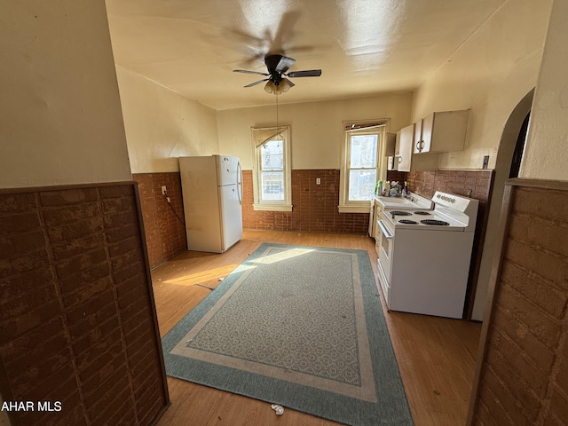 kitchen with light hardwood / wood-style flooring, ceiling fan, washer / dryer, white refrigerator, and brick wall