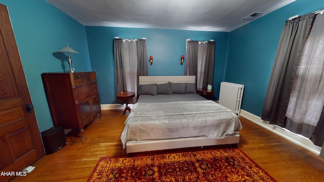 bedroom with wood-type flooring and radiator heating unit