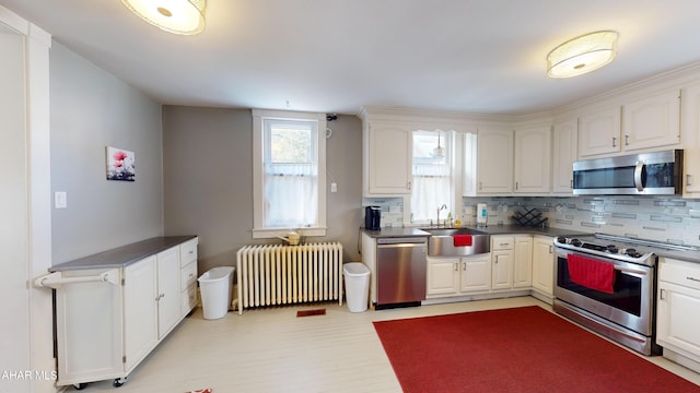 kitchen with white cabinets, sink, radiator heating unit, and stainless steel appliances