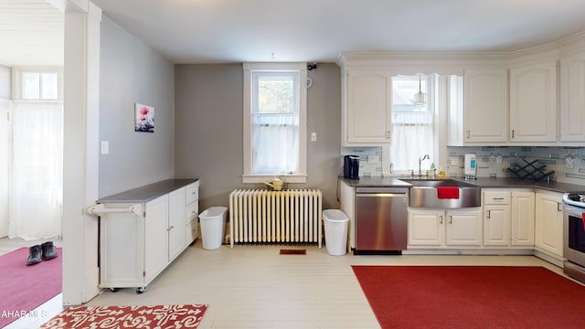 kitchen with radiator heating unit, sink, stainless steel appliances, backsplash, and white cabinets