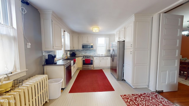 kitchen featuring radiator, white cabinetry, and appliances with stainless steel finishes