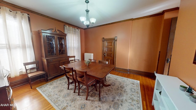 dining room featuring hardwood / wood-style flooring, crown molding, radiator, and a notable chandelier