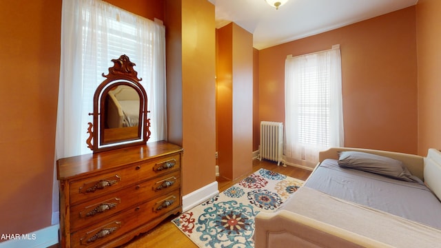 bedroom featuring radiator heating unit and light hardwood / wood-style floors