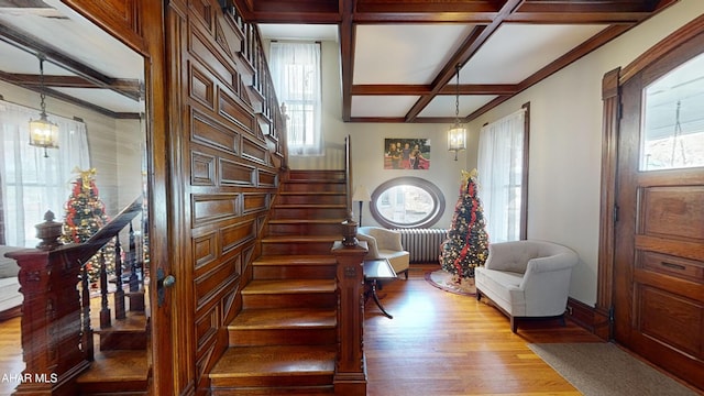 stairs with hardwood / wood-style floors, beam ceiling, a wealth of natural light, and coffered ceiling