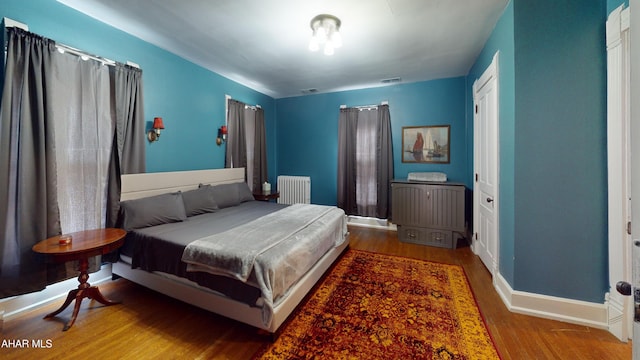 bedroom featuring radiator heating unit and wood-type flooring