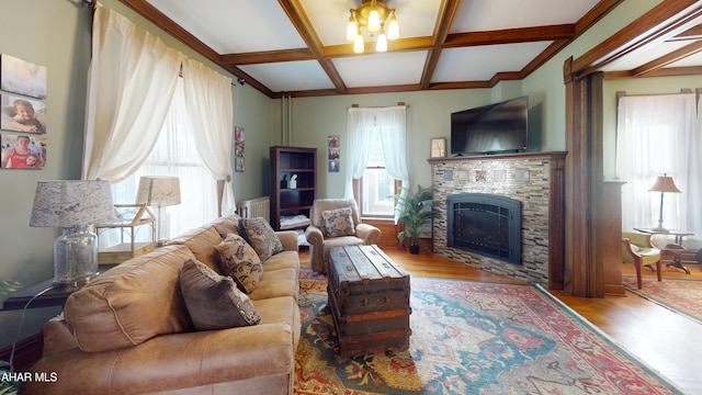 living room with light wood-type flooring, coffered ceiling, a notable chandelier, beamed ceiling, and a stone fireplace