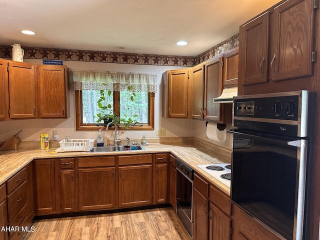 kitchen featuring sink, light hardwood / wood-style flooring, ventilation hood, white electric cooktop, and black oven