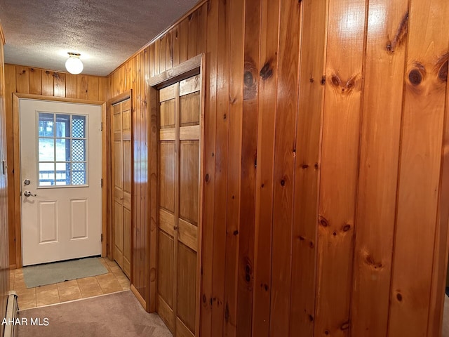 doorway featuring wooden walls, light carpet, and a textured ceiling