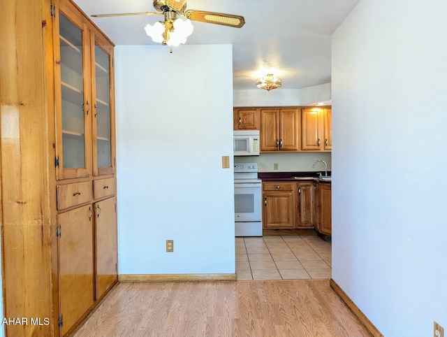 kitchen with white appliances, light hardwood / wood-style flooring, ceiling fan, and sink