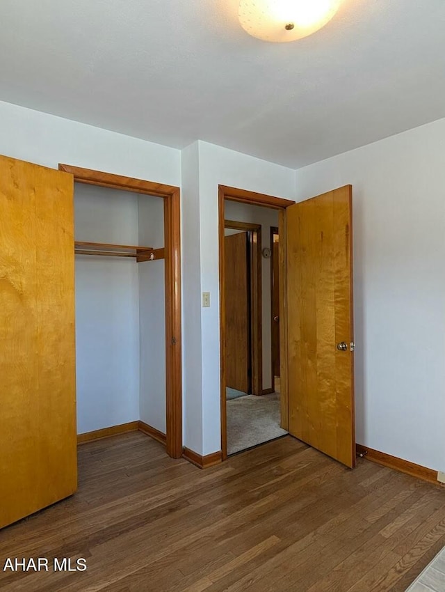 unfurnished bedroom featuring a closet and dark wood-type flooring