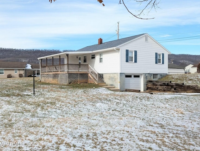 snow covered back of property with a garage