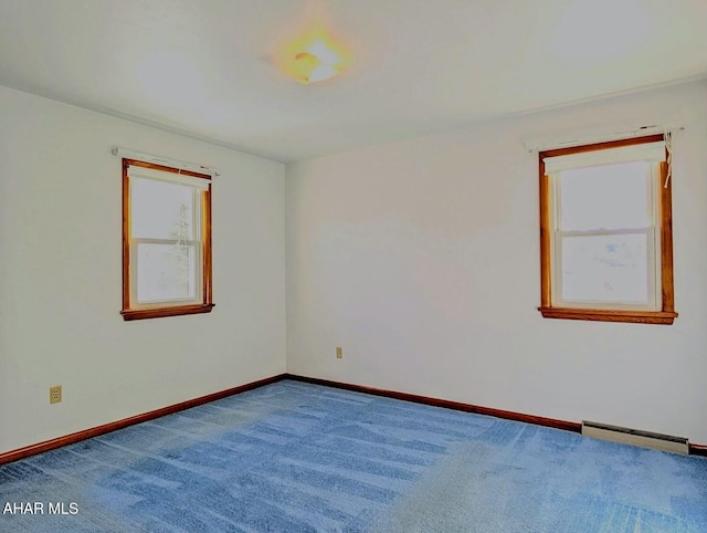 carpeted spare room with a baseboard heating unit