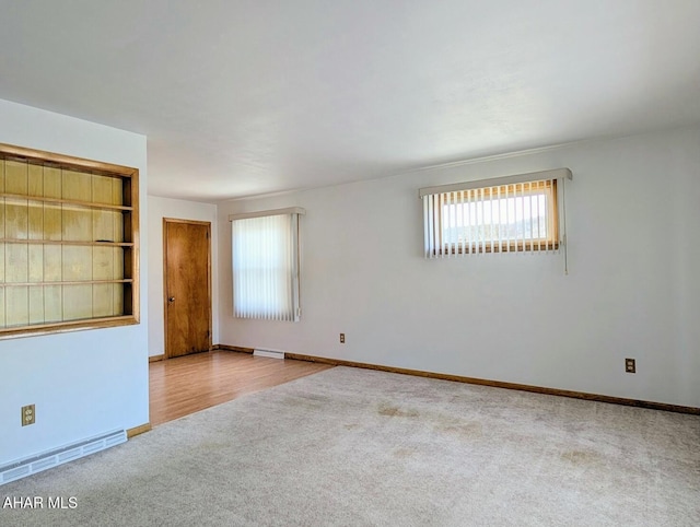 carpeted empty room featuring built in shelves and baseboard heating