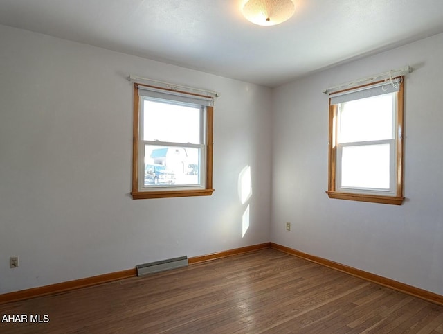 empty room with a wealth of natural light and dark hardwood / wood-style floors