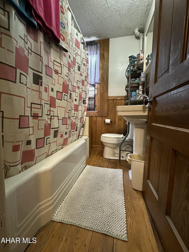 3785 Brumbaugh Rd, New Enterprise, PA 16664 - full bath with a textured ceiling, wainscoting, wood finished floors, and bathing tub / shower combination