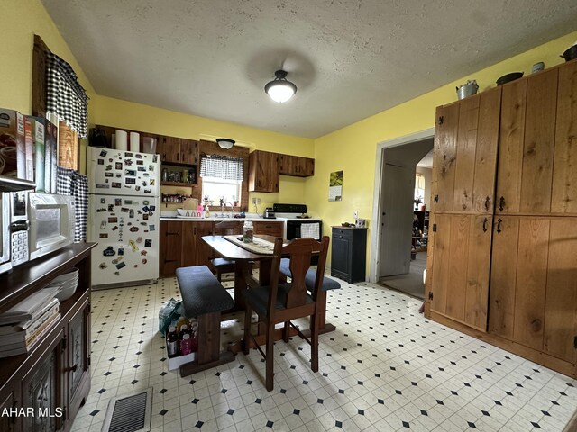 3785 Brumbaugh Rd, New Enterprise, PA 16664 - kitchen with freestanding refrigerator, light floors, black range with electric cooktop, light countertops, and a textured ceiling