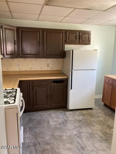 kitchen with a paneled ceiling and white appliances