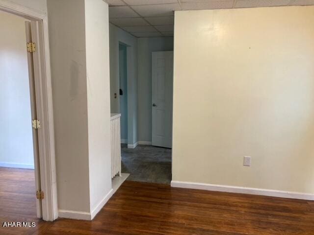 hall featuring a drop ceiling and dark wood-type flooring