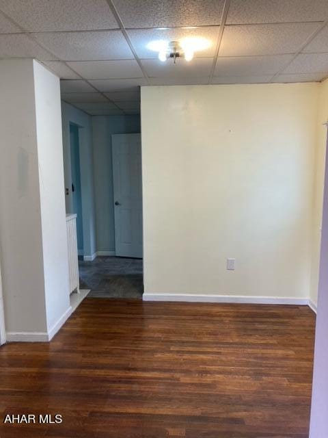 unfurnished room with a paneled ceiling and dark wood-type flooring